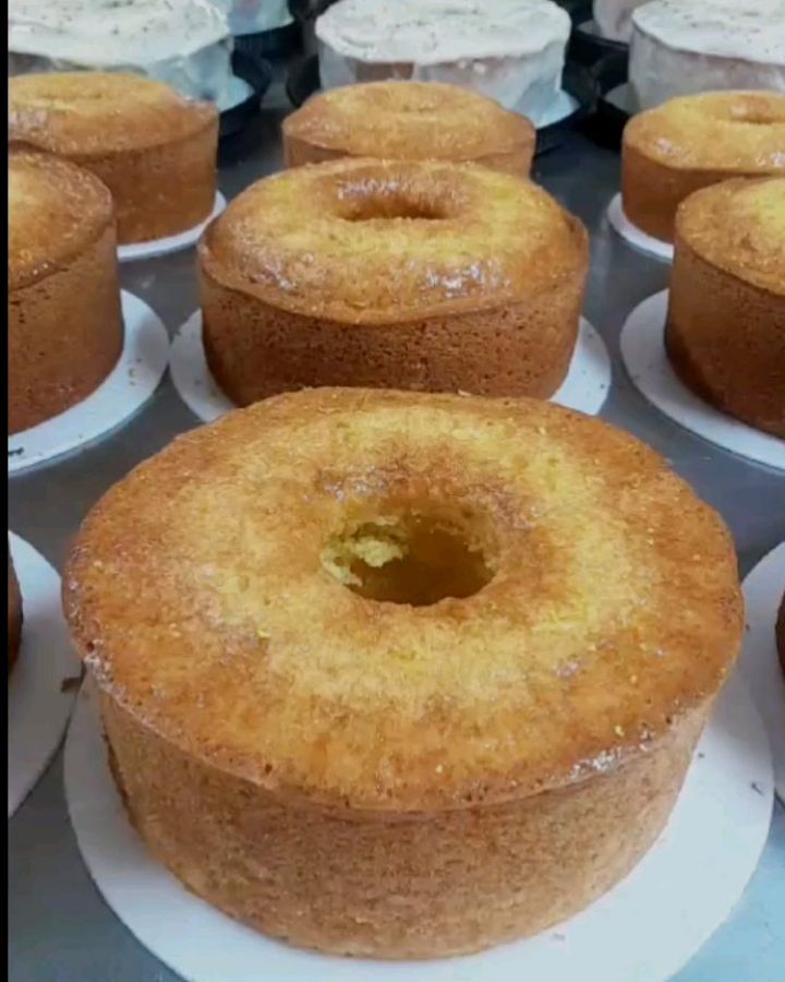 Fileira de bolos tradicionais recém-assados, prontos para cobertura, na cozinha da Bolo & Cia